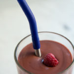 Photo of avocado raspberry and cocoa smoothie with a frozen raspberry in top