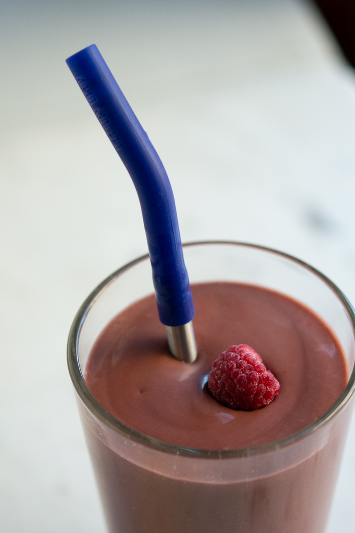 Photo of avocado raspberry and cocoa smoothie with a frozen raspberry in top