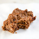 Photo of oat-y cocoa granola bar on a white napkin, with a bite out of it.