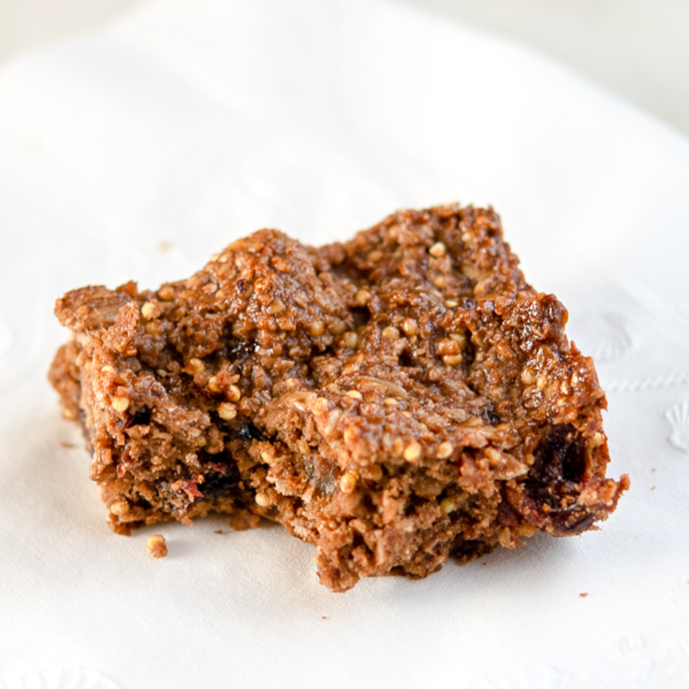 Photo of oat-y cocoa granola bar on a while napkin, with a bite out of it.