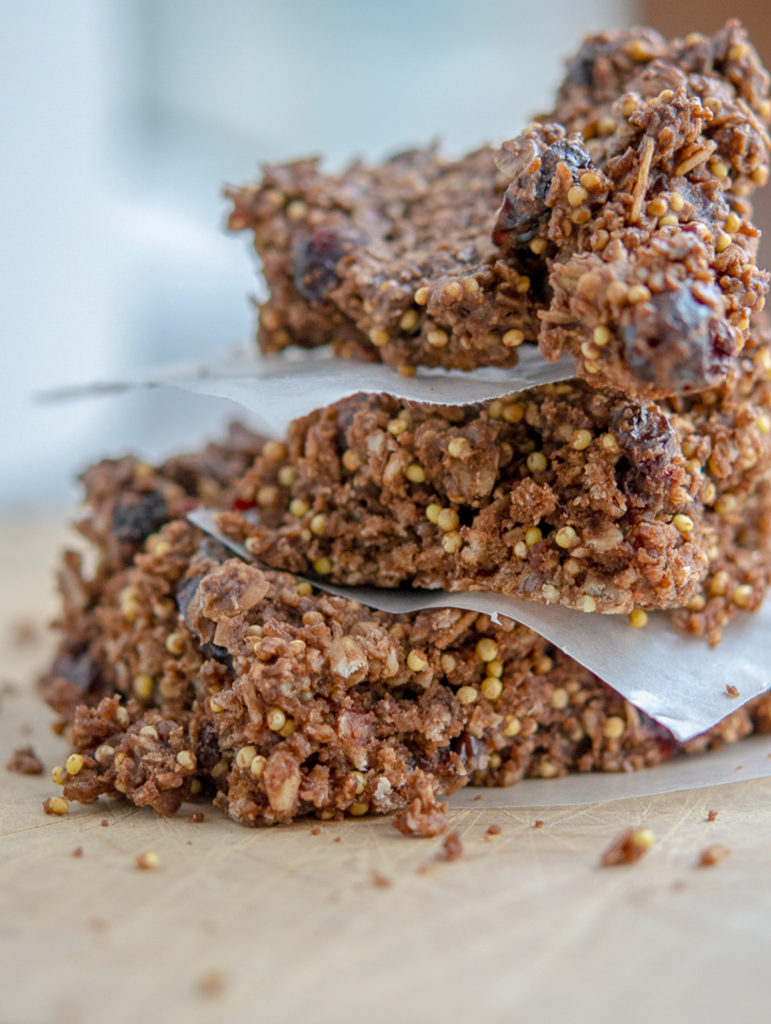 Photo of oat-y cocoa granola bar stacked between parchment paper