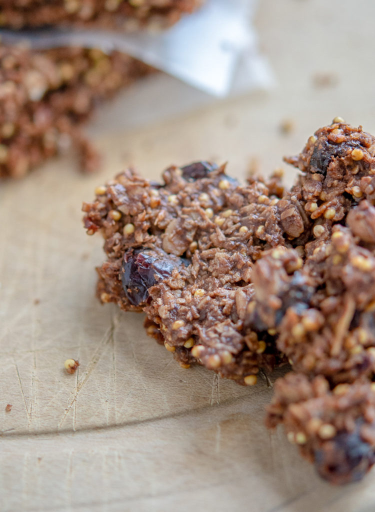 Photo of oat-y cocoa granola bar stacked between parchment paper