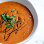 roasted tomato soup in a bowl with fresh basil garnish