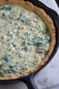 spinach and artichoke quiche uncooked in the pan