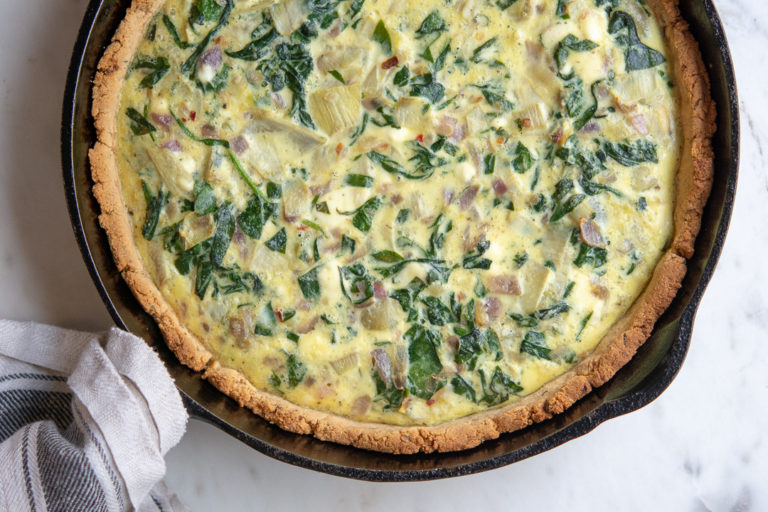 Overhead photo of spinach and artichoke quiche in cast iron pan