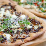 White whole wheat pizza crust with mushrooms, cheese and micro greens