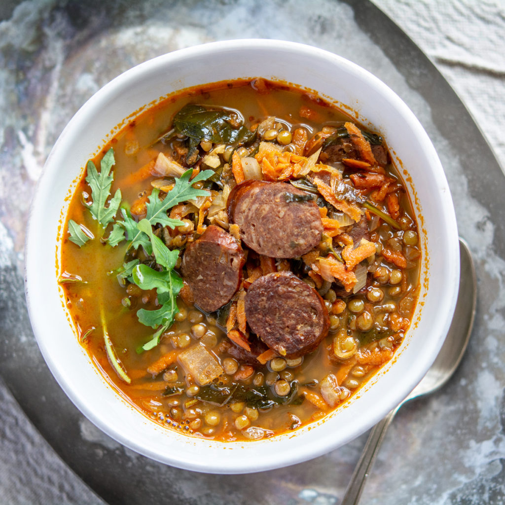 Overhead shot of lentil and chorizo soup with arugula