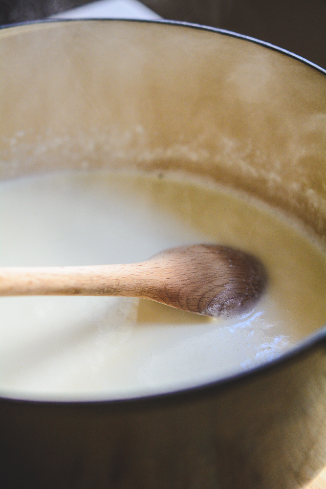 Ricotta Cheese milk in black pan with wooden spoon