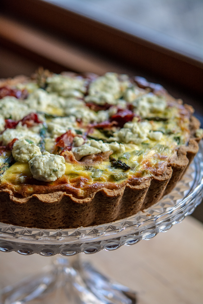 Baked asparagus and ricotta quiche on a pretty glass cake stand