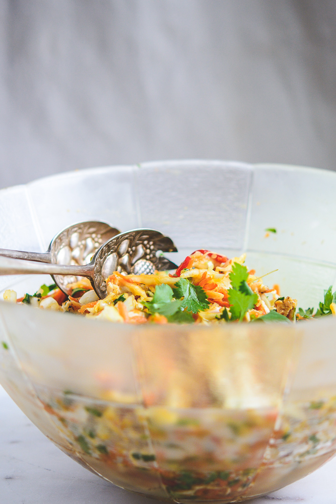 Chicken Cabbage Carrot Salad in a large glass bowl with silver salad servers