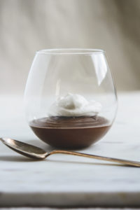Chocolate Mexican Pots de Creme with whipped cream in a stemless wineglass and a spoon