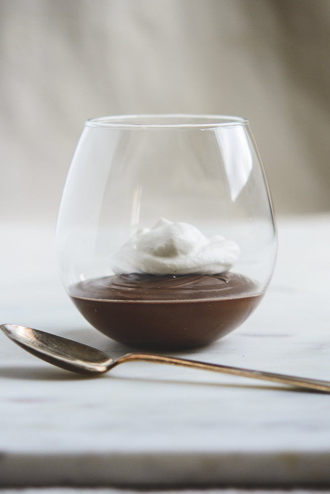 Chocolate Mexican Pots de Creme with whipped cream in a stemless wineglass and a spoon