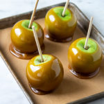 Caramel Apples on parchment on rimmed baking sheet