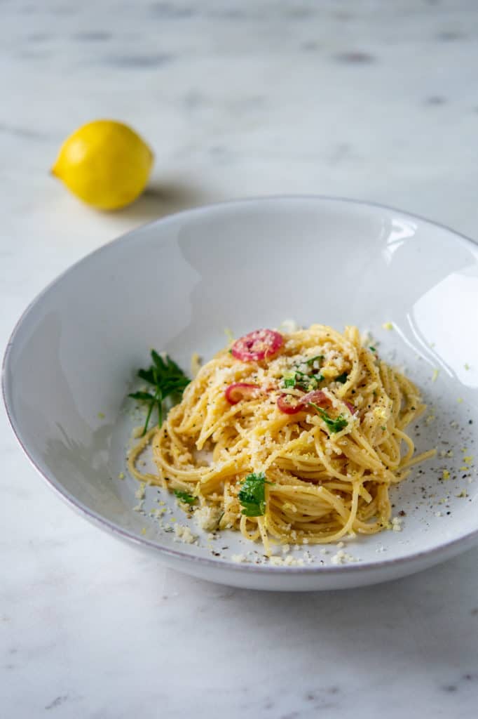 lemon pasta in a bowl and a lemon