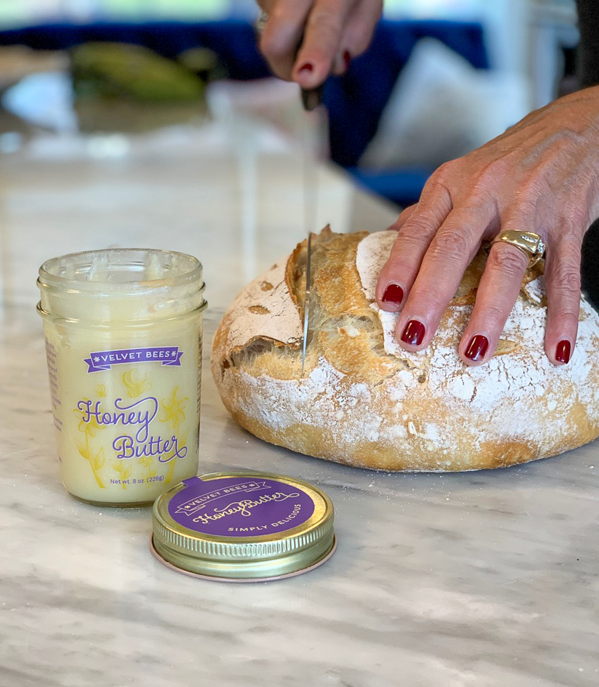 velvet bees honey butter and cutting a piece of fresh baked bread photo