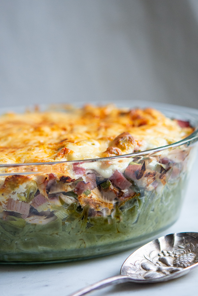 green noodle casserole in pan with silver spoon along side of it