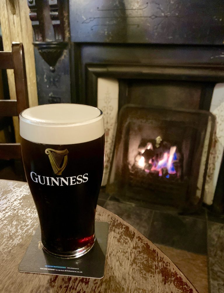 photo of a pint of Guinness in front of the fire