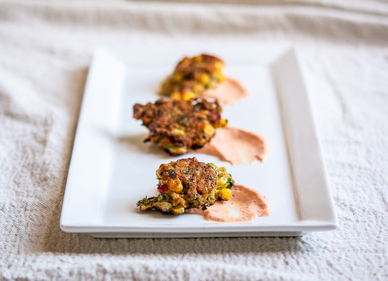 hero shot of corn zucchini fritters on a white plate