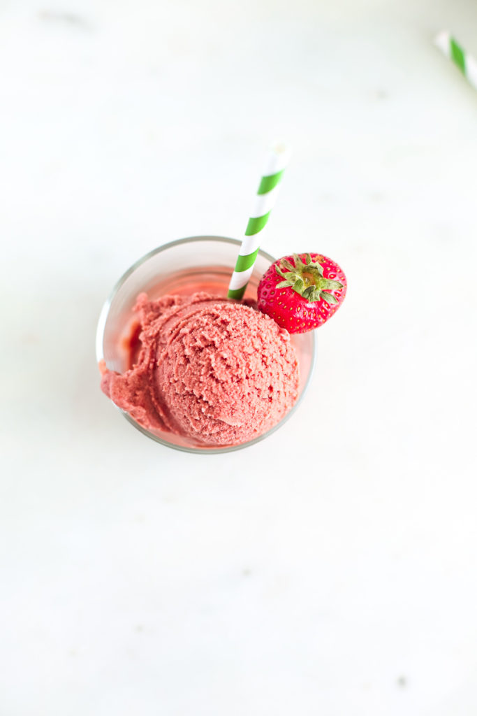 overhead shot of strawberry ice cream with green paper straw