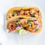 Overhead shot of Shrimp tacos on a skewer with lime wedges
