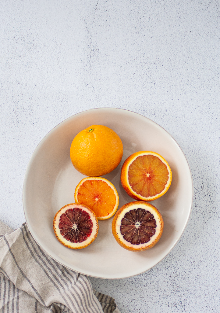 blood oranges in a bowl, some sliced, some whole