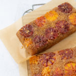 overhead shot of blood orange upside-down cake on parchment and a cooling rack