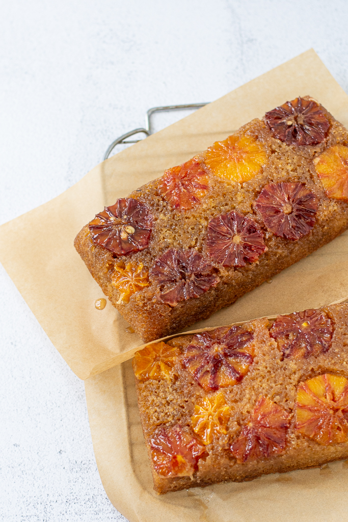 overhead shot of blood orange upside-down cake on parchment and a cooling rack