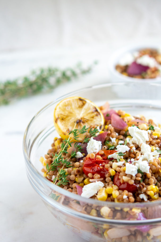 Israel Couscous Tomato and Corn Salad with Goat Cheese with lemon in the bowl