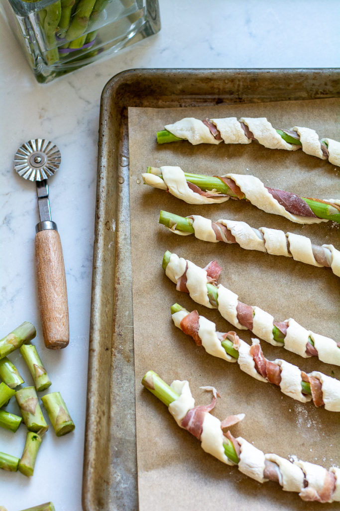 unbaked asparagus and prosciutto wrapped in puff pastry in sheet pan
