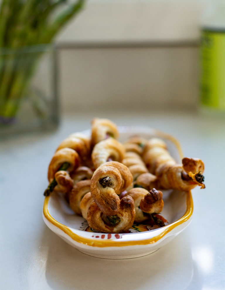 asparagus and prosciutto wrapped in puff pastry on a serving trayy