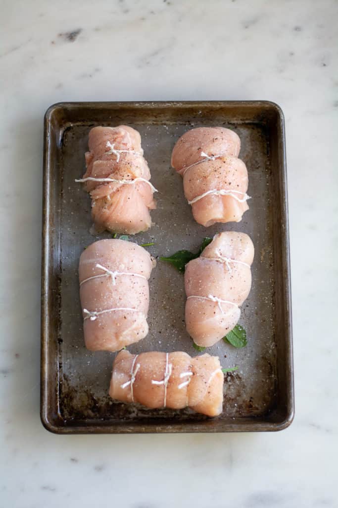 rolled, raw chicken breasts on sheet pan
