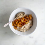 toasted oats and vanilla applesauce in a ceramic bowl with silver spoon