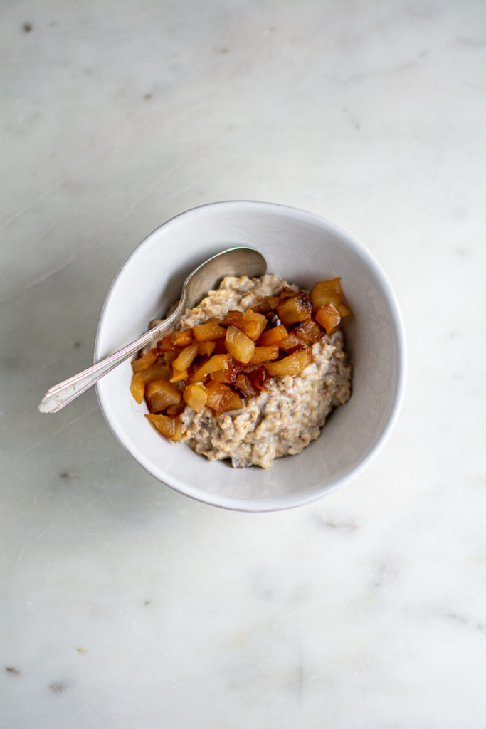 toasted oats and vanilla applesauce in a ceramic bowl with silver spoon