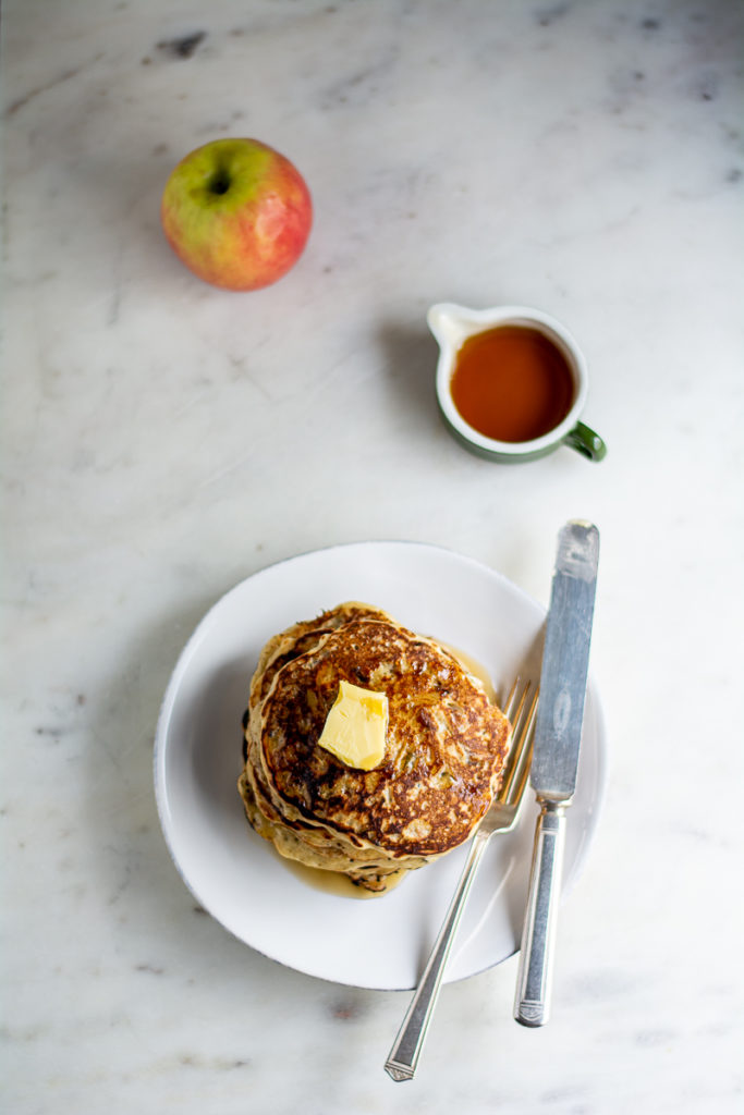 long overhead shot of wild rice and almond pancakes with apple and syrup