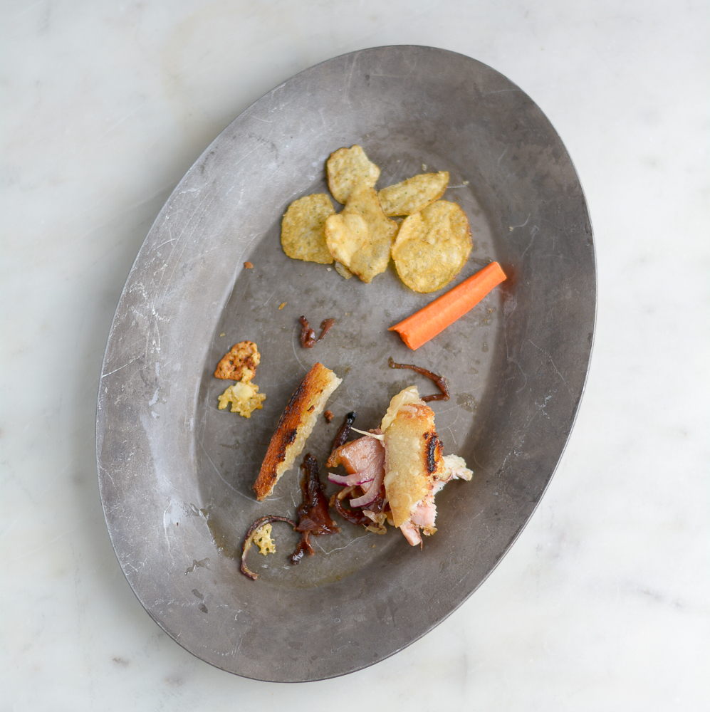 overhead shot of a mostly eaten cheese toastie, chips and carrots