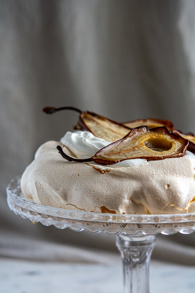 Straight on shot of Roasted Pear Pavlova on a crystal cake stand