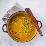 Overhead shot of Irish Vegetable soup in a dutch oven with towel and wooden spatula