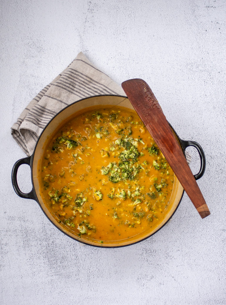 Overhead shot of Irish Vegetable soup in a dutch oven with towel and wooden spatula