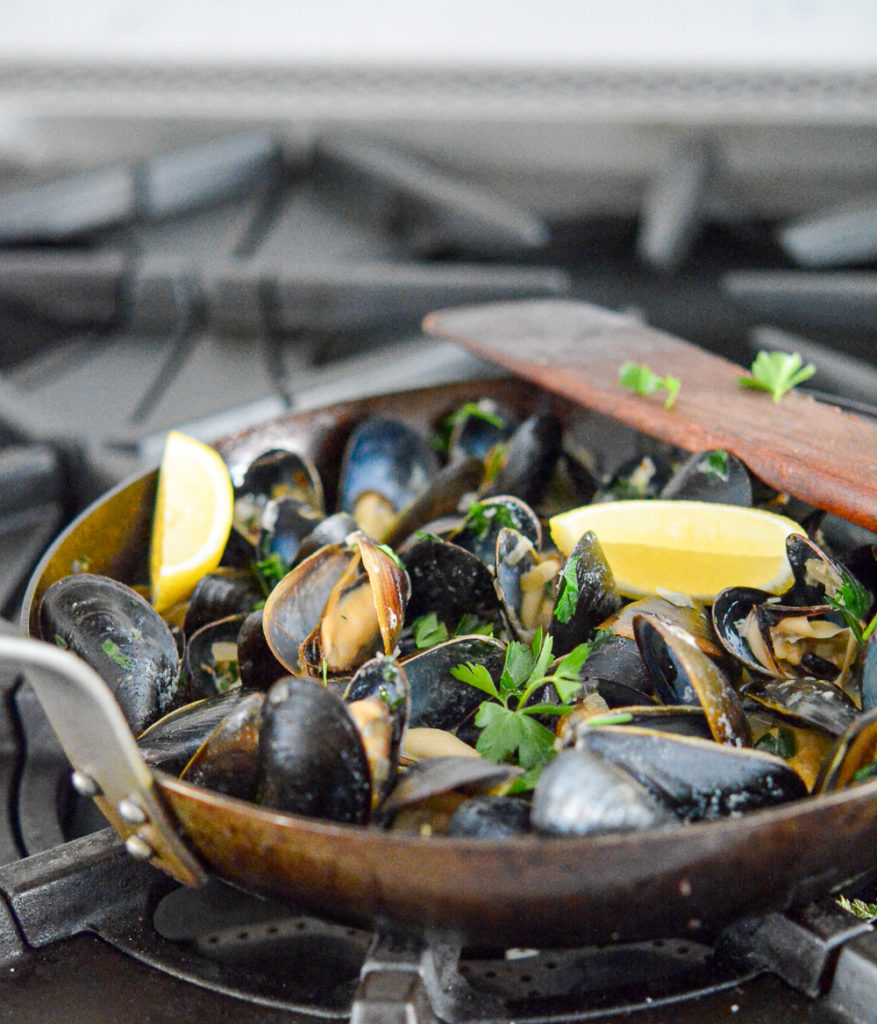 garlic and guinness mussels in a pan with a lemon wedge