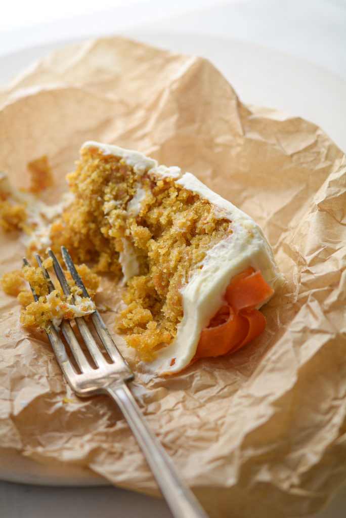 Carrot Ginger Cake with White Chocolate Cream Cheese Frosting slice on parchment paper with a fork