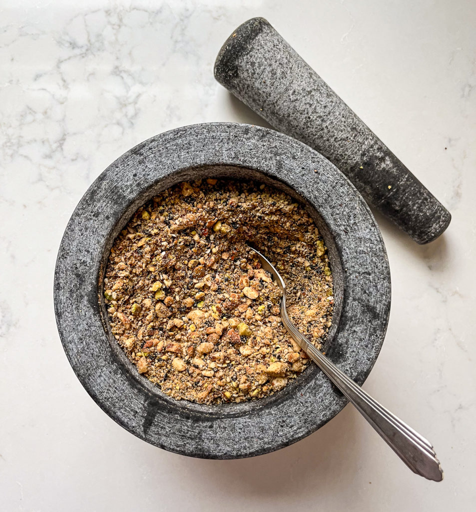 dukkah in a mortar and pestle with a spoon