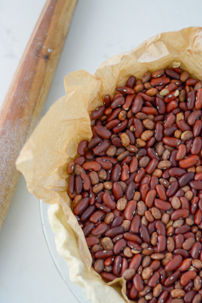 dry beans in a pie plate with rolling pin