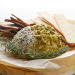 Cheeseball overhead shot on a round board with parchment, crackers and spreader