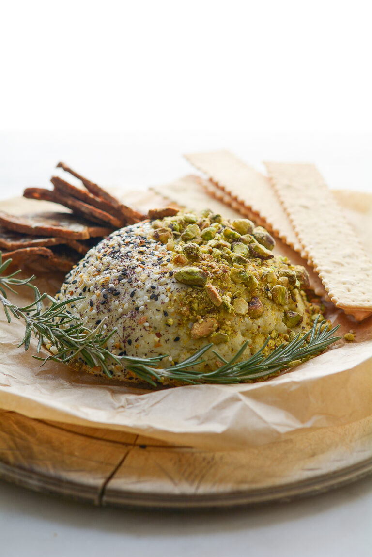 Cheeseball overhead shot on a round board with parchment, crackers and spreader