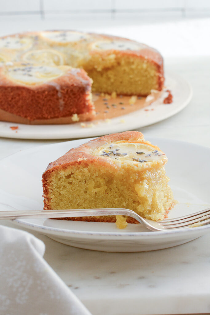 Photo of piece of lemon olive oil cake with lemon drizzle and fork with napkin