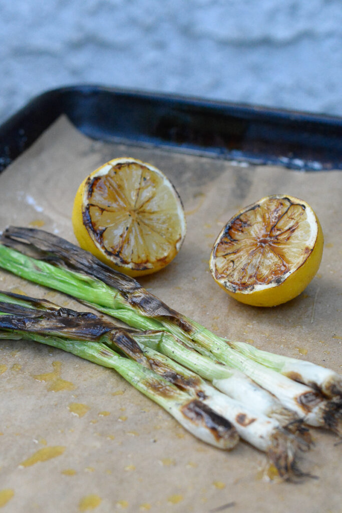 grilled scallions and grilled lemon halves on a sheet pan