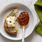 Black Garlic and Tomato Chutney on a spoon with bread and goat cheese
