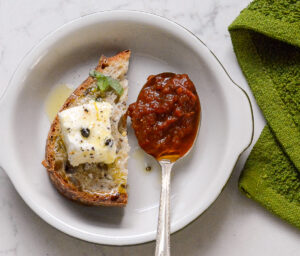 Black Garlic and Tomato Chutney on a spoon with bread and goat cheese