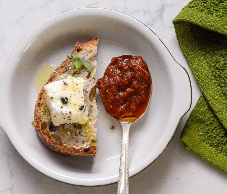 Black Garlic and Tomato Chutney on a spoon with bread and goat cheese
