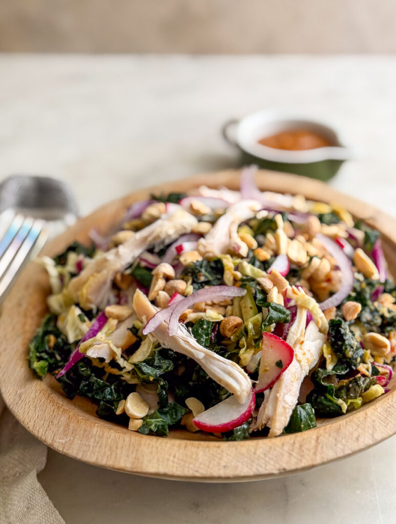 Overhead shot of Kale Peanut Salad with Chicken in a wooden bowl
